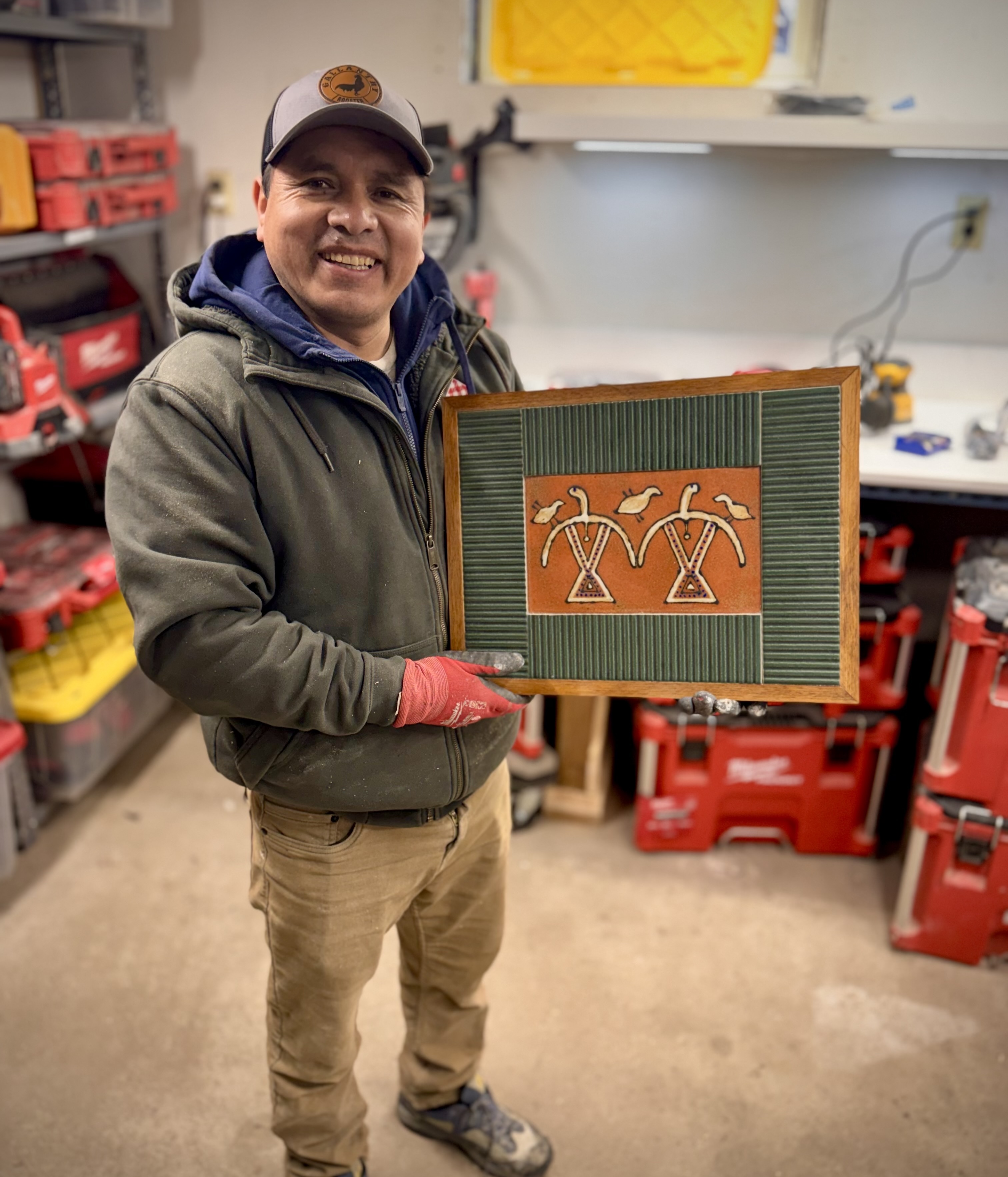 Alfonso holding one of his handcrafted wood art pieces
